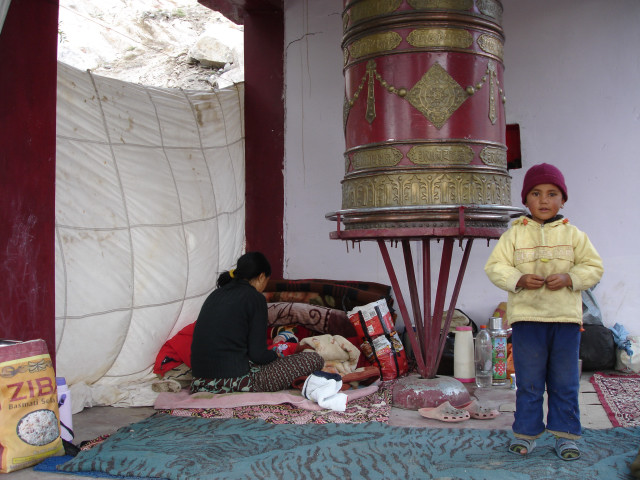 Local child camping out next to a Prayer Wheel