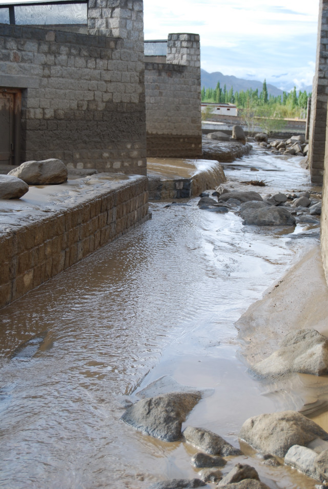 Mud and water ...|<b>flowing down the east side of the campus between the latrines and the classrooms</b>